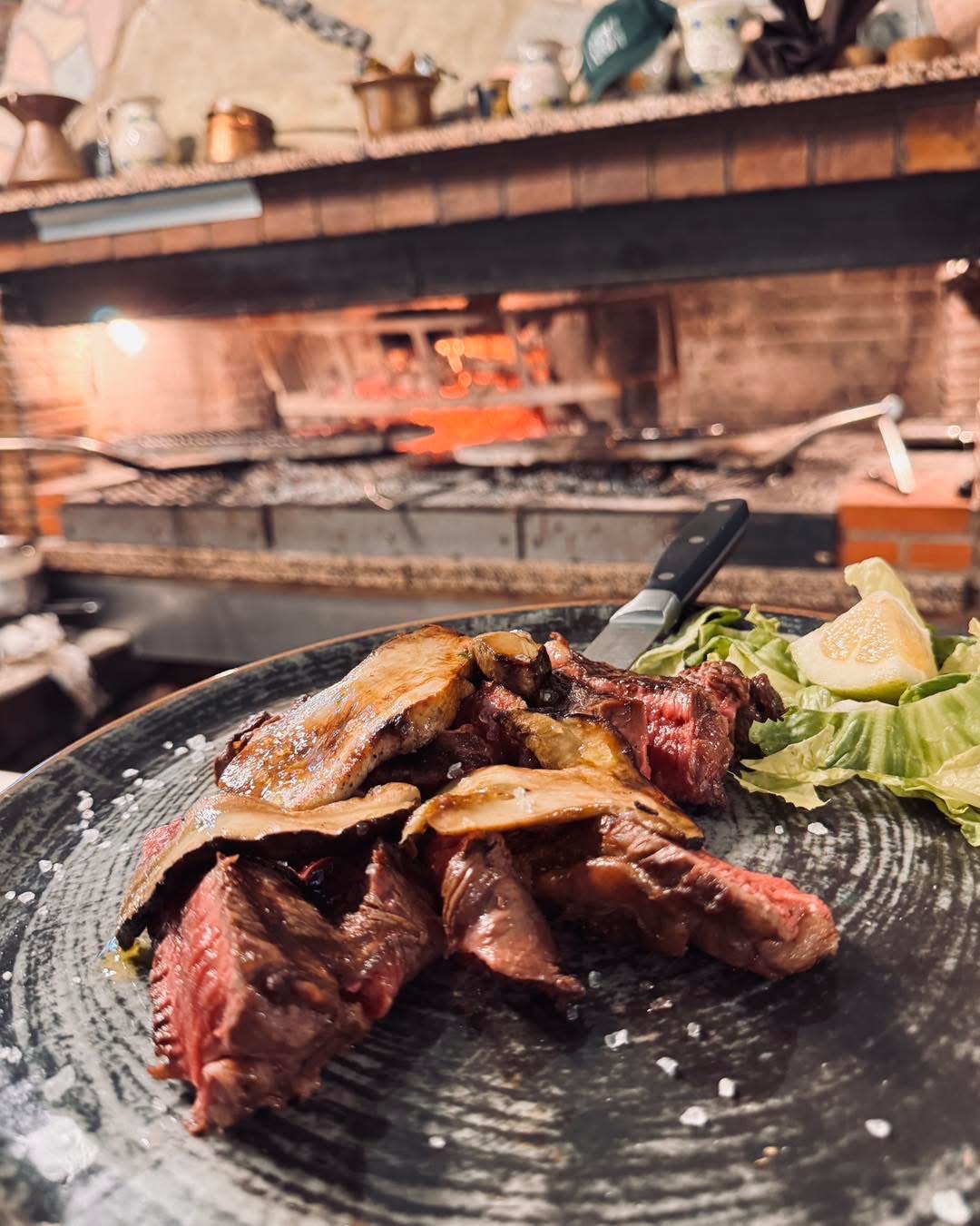 Carne servita su piatto con brace sullo sfondo